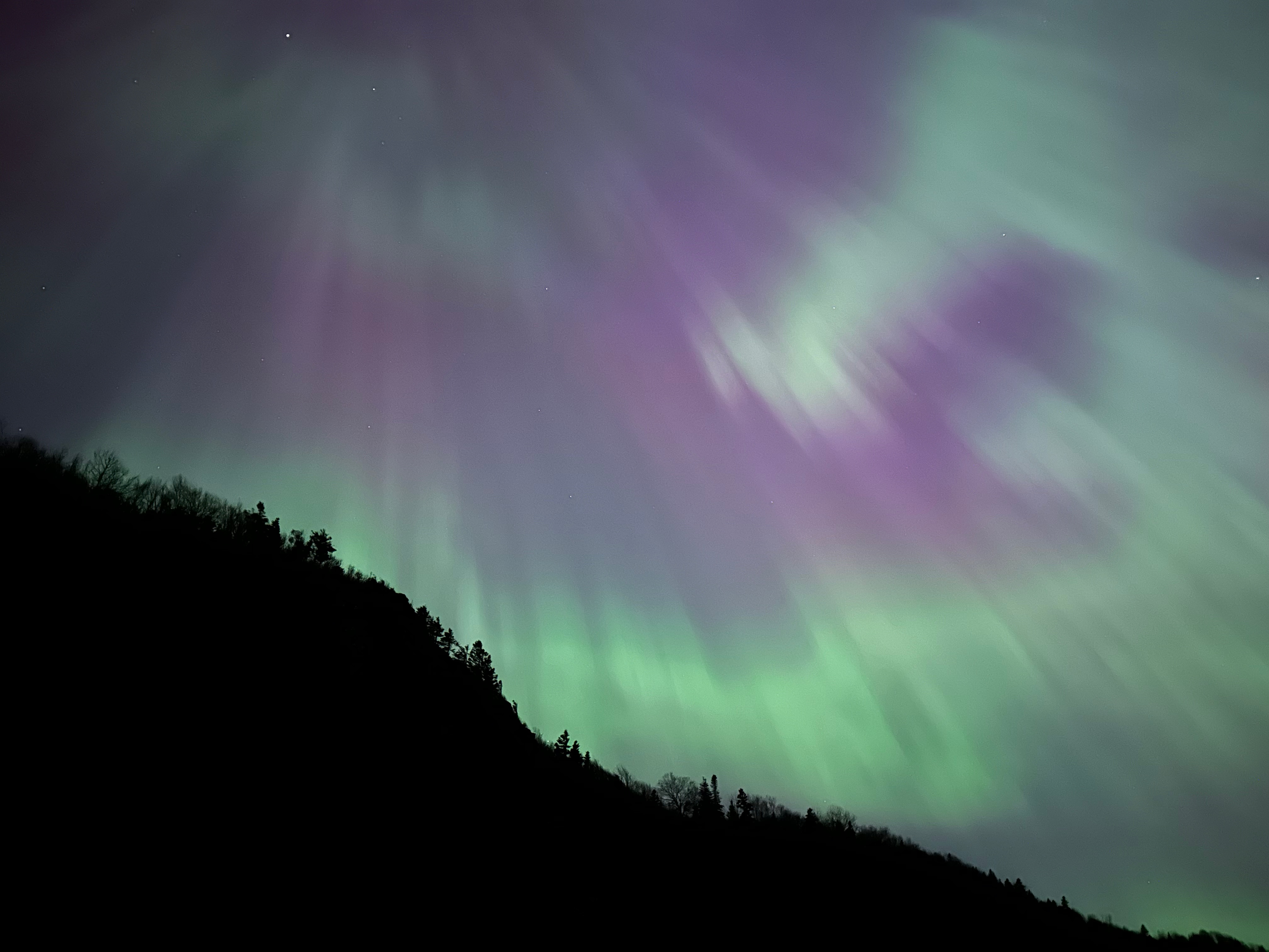 Aurora borealis over a dark hillside